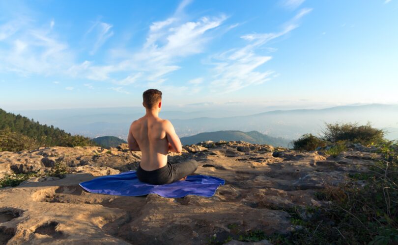 man meditating in rocky landscape